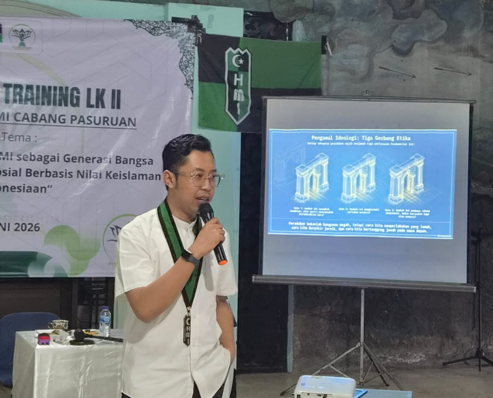 Potret Achmad Faizal N. Kuncoro, Wakil Sekretaris Jenderal PB HMI, sedang memberikan presentasi dalam acara HMI Cabang Pasuruan. Di belakangnya terlihat spanduk "TRAINING LK II" dan layar proyektor. HMI (Himpunan Mahasiswa Islam) memberikan dukungan terhadap pengusutan dugaan korupsi oleh Kortastipidkor Polri.